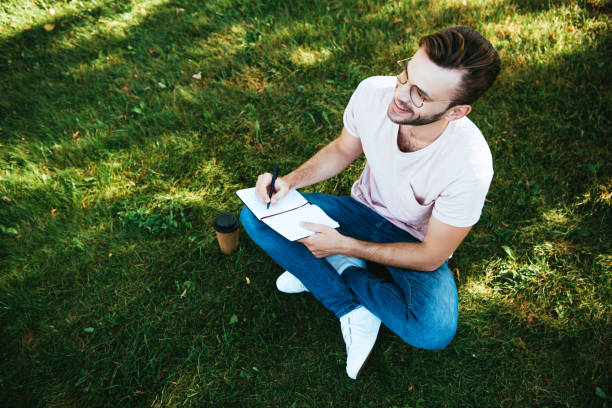 istock high angle view of handsome man making notes on green grass in park 1056669910