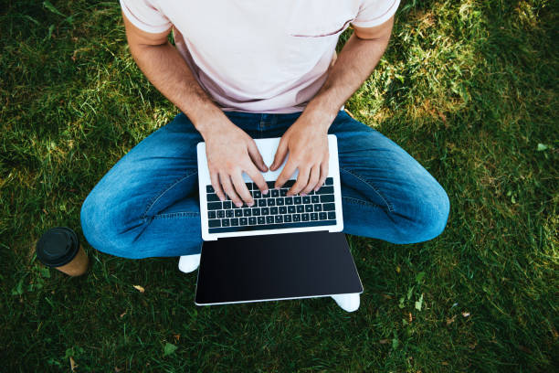 istock cropped image of man using laptop with blank screen on green grass 1056669926