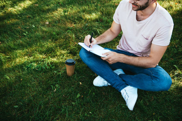 istock cropped image of man making notes on green grass in park 1056669934
