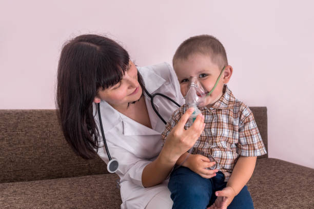 Doctor helping to little boy with nebulizer mask Doctor helping to little boy with nebulizer mask pediatric nebulizer mask stock pictures, royalty-free photos & images