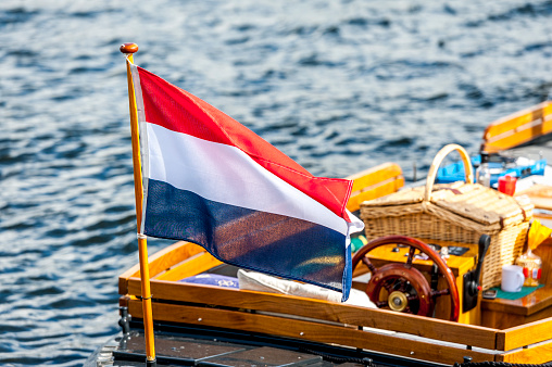 Achterkant van een sloep met close up van Nederlandse vlag op een zomerse dag.