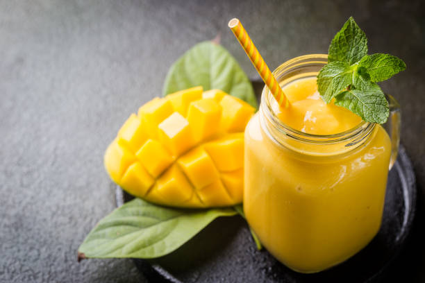 Healthy mango smoothie Refreshing and healthy mango smoothie in a glass with fresh fruit over stone background with copy space smoothie stock pictures, royalty-free photos & images