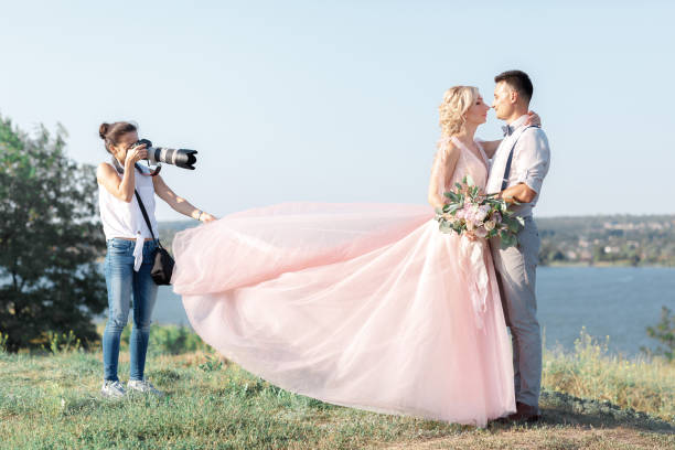 wedding photographer takes pictures of bride and groom wedding photographer takes pictures of bride and groom in nature. wedding couple on photo shoot. photographer in action wedding photos stock pictures, royalty-free photos & images