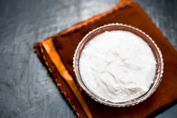 Close up of plain curd or yogurt or dahi in transparent glass bowl on a brown cloth or napkin on wooden surface. Close up of plain curd or yogurt or dahi in transparent glass bowl on a brown cloth or napkin on wooden surface. curd cheese photos stock pictures, royalty-free photos & images