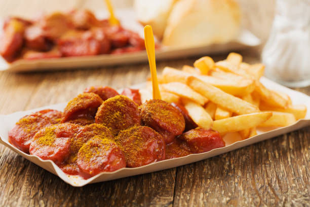 istock Traditional German currywurst, served with chips on disposable paper tray. 1056690100
