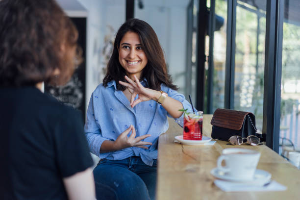 deux jeune femme parle en langue des signes - non verbal communication photos et images de collection