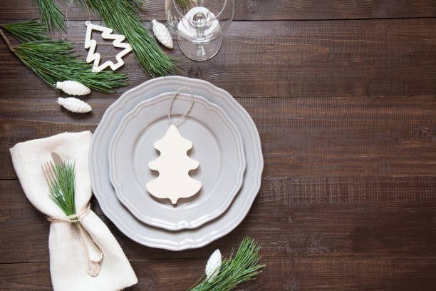istock Christmas table setting with white wooden decor, silverware and decorations on wooden board. Top view. Rustic style. 1056700738