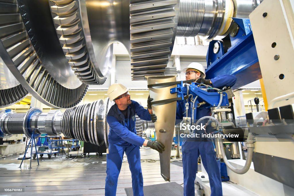 workers assembling and constructing gas turbines in a modern industrial factory Industry Stock Photo