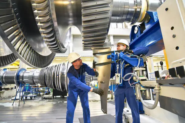 Photo of workers assembling and constructing gas turbines in a modern industrial factory