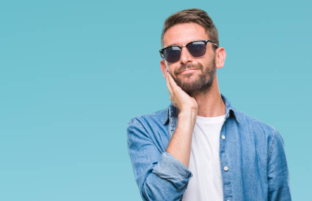 istock Young handsome man wearing sunglasses over isolated background with hand on chin thinking about question, pensive expression. Smiling with thoughtful face. Doubt concept. 1056716114