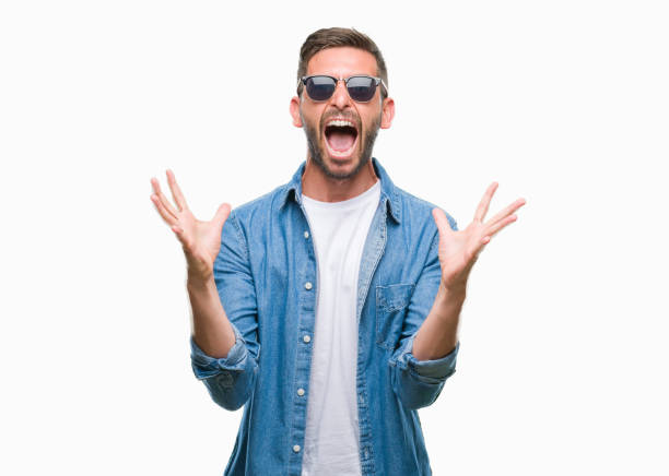 istock Young handsome man wearing sunglasses over isolated background celebrating crazy and amazed for success with arms raised and open eyes screaming excited. Winner concept 1056716124