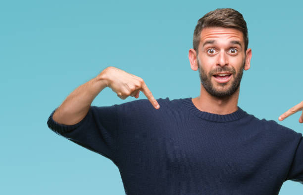 istock Young handsome man wearing winter sweater over isolated background looking confident with smile on face, pointing oneself with fingers proud and happy. 1056716430