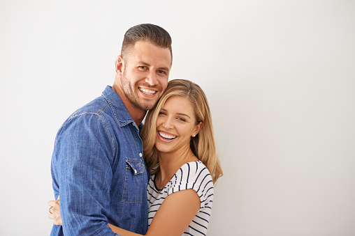 Portrait of a happy and loving young couple embracing each other against a gray wall
