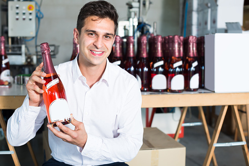 Man holding bottle of wine in packing  section of wine factory