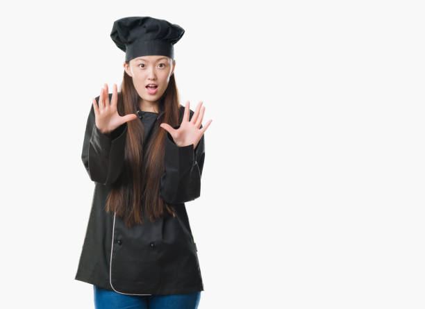 istock Young Chinese woman over isolated background wearing chef uniform afraid and terrified with fear expression stop gesture with hands, shouting in shock. Panic concept. 1056731082