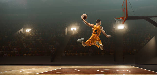 Basketball player scoring. Slam Dunk Young muscular basketball player with a ball on floodlight professional court scoring a goal basketball sport stock pictures, royalty-free photos & images