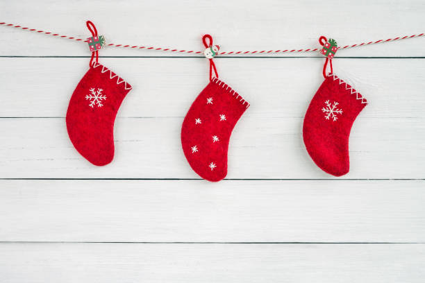 istock Three red Christmas socks hanging on the rope on white wooden background. Copy space 1056735808