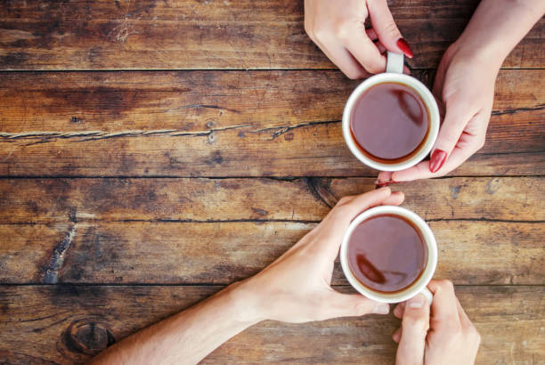 Cups of drink in the hands of lovers on sofa