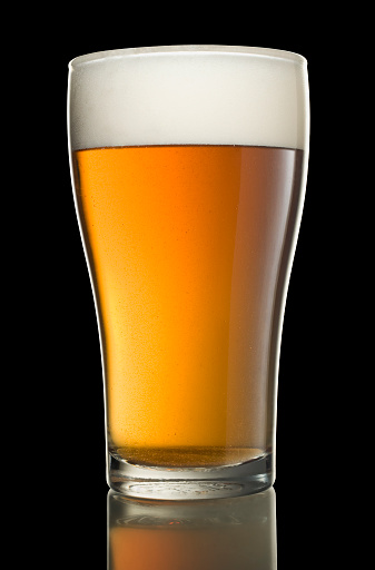 Glass of beer isolated on black using dark field technique, with faint reflection.