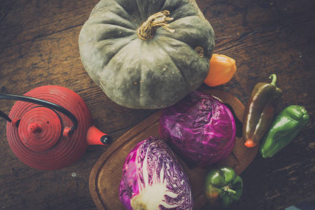 Rustic table with autumn vegetables and a tea pot. stock photo