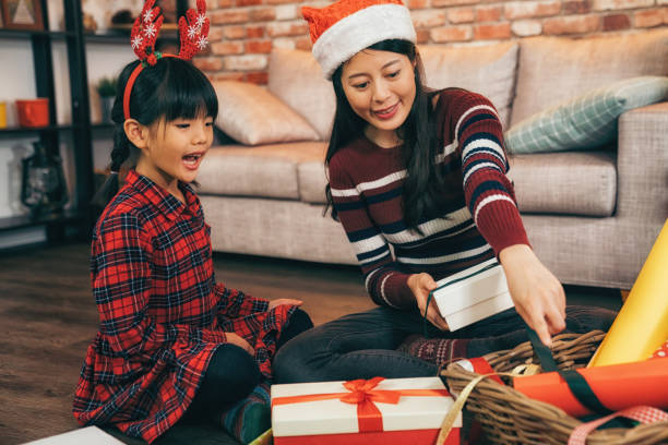 istock mom and her child wrapping present for Xmas. 1056745836