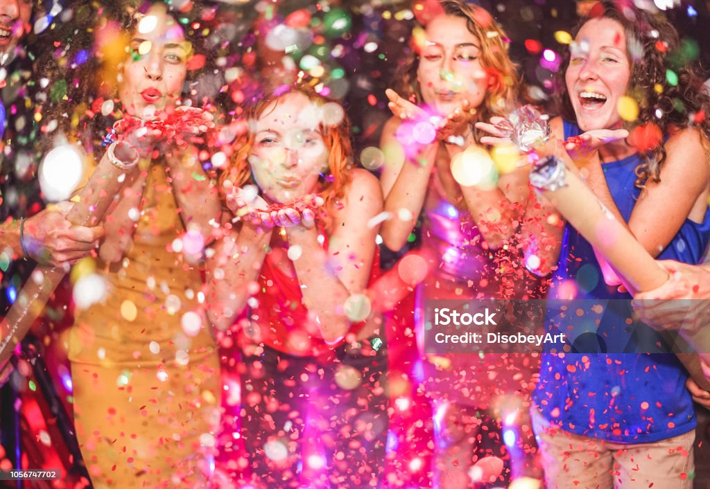 Happy friends making party throwing confetti - Young people celebrating on weekend night - Entertainment, fun, new year's eve, nightlife and fest concept - Focus on red hair girl hands Party - Social Event Stock Photo