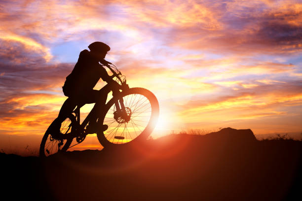 silueta de ciclista de montaña en acción contra el concepto de puesta de sol para deporte y ejercicio - mountain biking fotografías e imágenes de stock