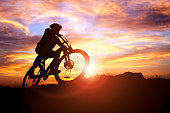 Mountain biker silhouette in action against the sunset concept for sport and exercise