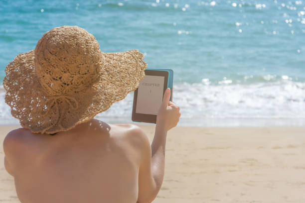 istock Woman reading an e-book on vacation on the beach 1056758192
