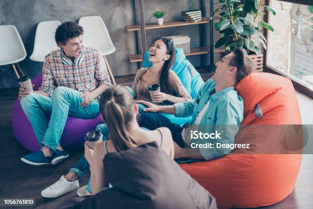 Rejoice And Cheerful Trandy Youths Sitting In A Loft Style Room With Coffee In Hands Tell Funny Stories And Humorous Joke To Each Other And Aloud Laugh Without Restraint With Big Toothy Smile Stock Photo - Download Image Now