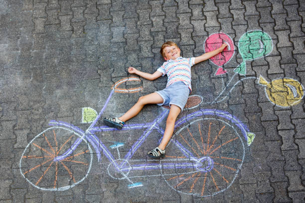 istock little kid boy having fun with bicycle chalks picture on ground 1056766358