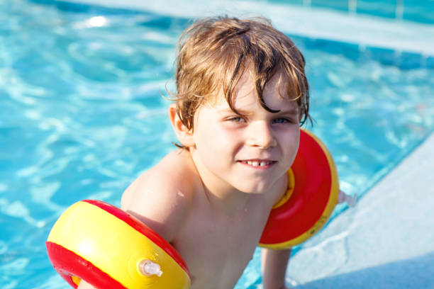 istock Happy little kid boy having fun in an swimming pool 1056772168