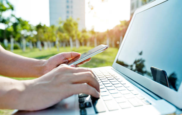 istock Human hand holding mobile phone and typing on laptop 1056773754
