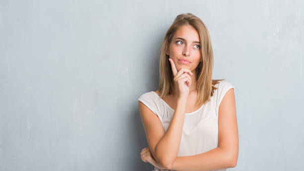 istock Beautiful young woman standing over grunge grey wall serious face thinking about question, very confused idea 1056773918