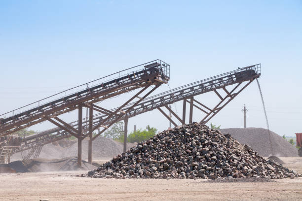 Crushing machinery, cone type rock crusher, conveying crushed granite gravel stone in a quarry open pit mining. Processing plant for crushed stone and gravel. Mining and Quarry mining equipment. maquinaria de trituración, la trituradora del cono tipo roca, transporta grava de granito triturado en una minería a cielo abierto mina. planta de procesamiento de piedra triturada y grava. minería y equipo de explotación minera de la mina.