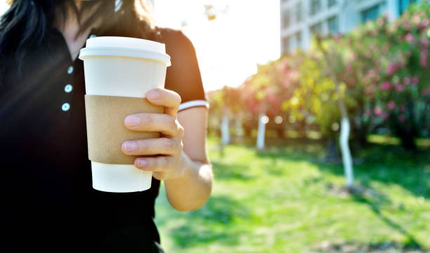 Woman's hand holding a paper coffee cup.