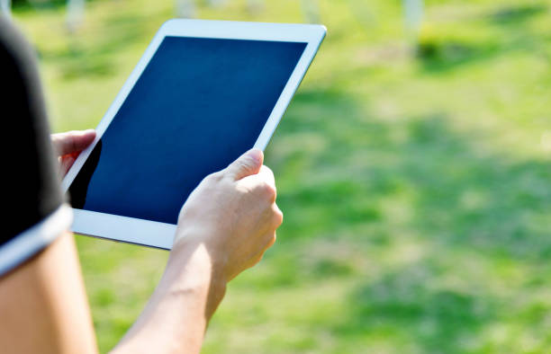 istock Woman hand using a digital tablet outdoors 1056777994