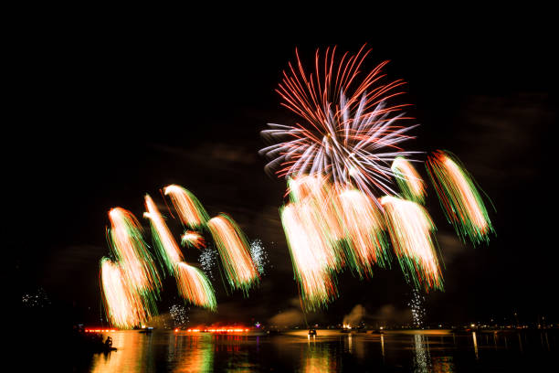 Huge colorful fireworks explosions and fire rain in the night at a lake Huge colorful fireworks explosions and fire rain in the night at a lake hogmanay photos stock pictures, royalty-free photos & images