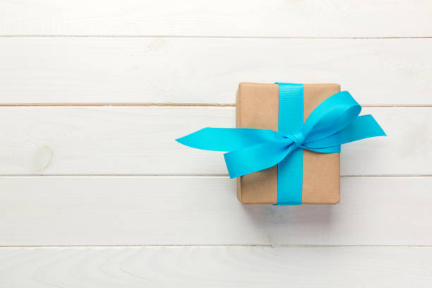 istock Beautiful gift box with a blue bow on the white wooden table. top view 1056781736