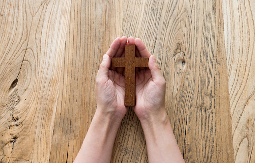 Woman hand holding a wooden cross.