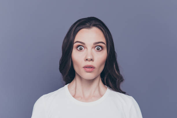 boo ! portrait d’attractif assez charmant élégant peur brune aux cheveux bouclés fille en t-shirt blanc avec les yeux grands écarquillés, isolé sur fond gris - regarder fixement photos et images de collection