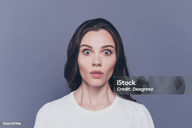 Boo Portrait Of Attractive Pretty Charming Stylish Afraid Brunette Curlyhaired Girl In White Tshirt With Staring Big Eyes Isolated Over Grey Background Stock Photo - Download Image Now