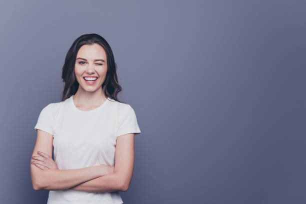 istock Adorable attractive nice charming gorgeous curly-haired brunette caucasian smiling winking young girl with folded hands. Copy space. Isolated over grey background 1056782768