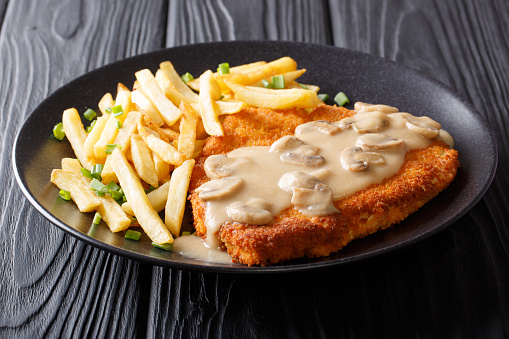Crispy Fried Pork Chops (Jaeger Schnitzel) with sauce and french fries close-up on a plate. Horizontal