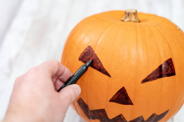 istock Drawing a pumpkin face for Halloween 1056787646