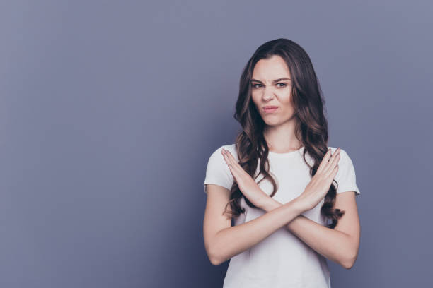 retrato de atraente garota legal muito elegante cabelo encaracolado em casual branco t-shirt, mostrando rejeita o sinal com os braços cruzados, isolados sobre fundo cinza - protest stop gesture stop sign no - fotografias e filmes do acervo