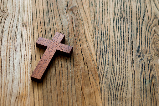 Wooden cross on desk background.