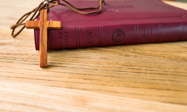 istock Closed bible and cross on wooden desk 1056793132
