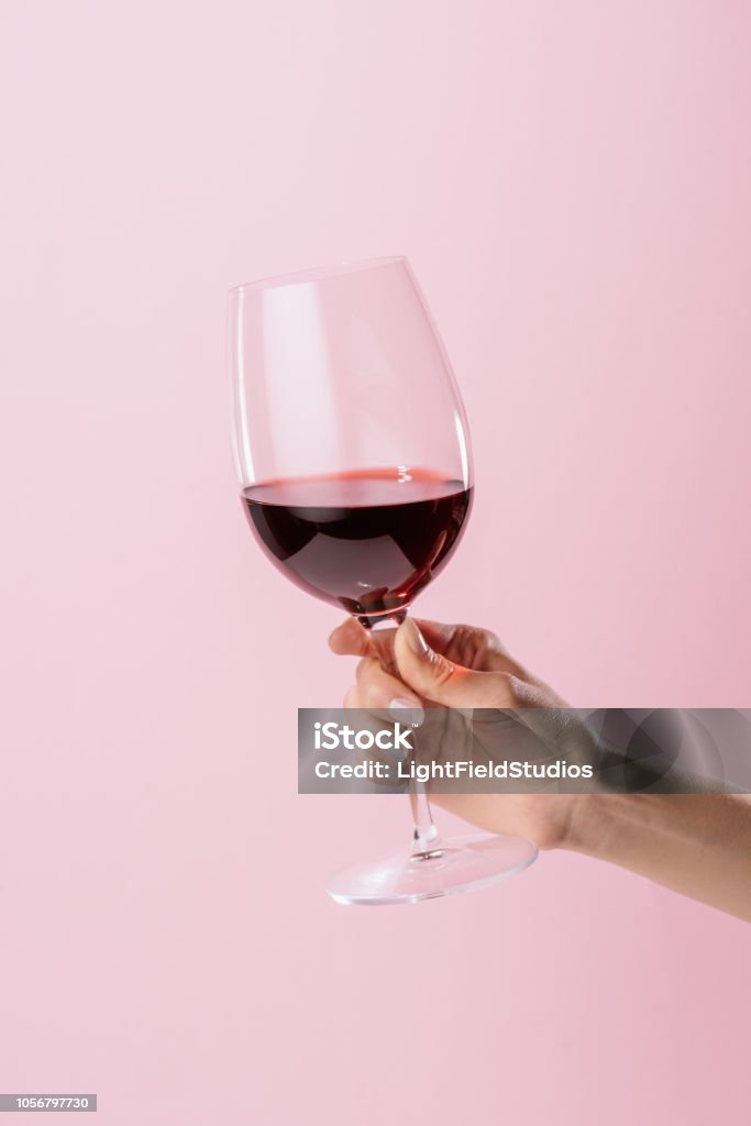 tiro recortado de mulher segurando o copo de vinho tinto, isolado em rosa - Foto de stock de Vinho royalty-free