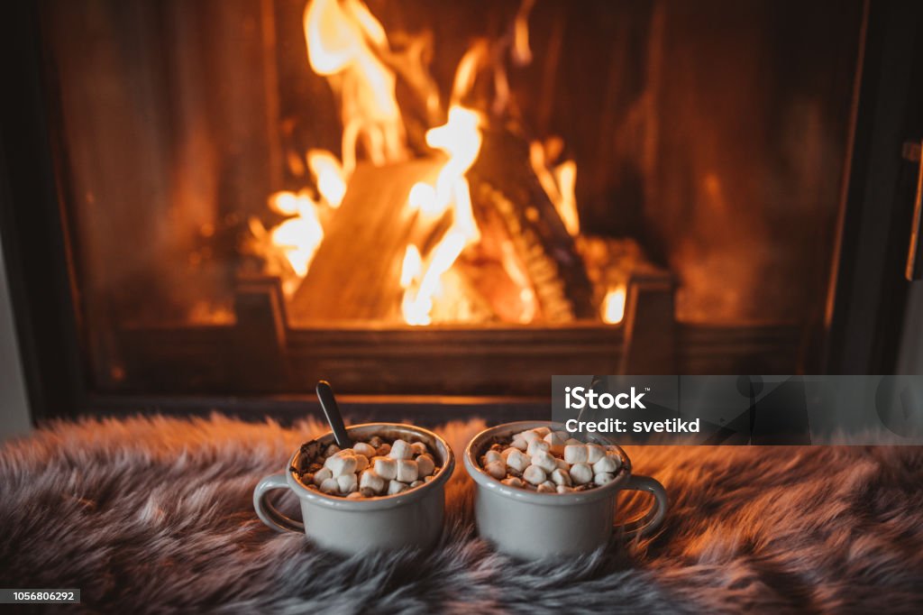 Cozy winter drink Cups with hot chocolate on fur, fireplace in background Fireplace Stock Photo